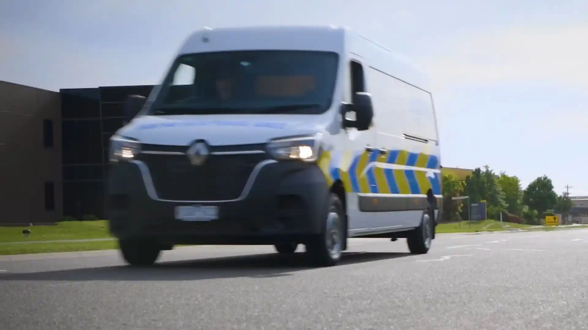 Service van driving on a road near a commercial building