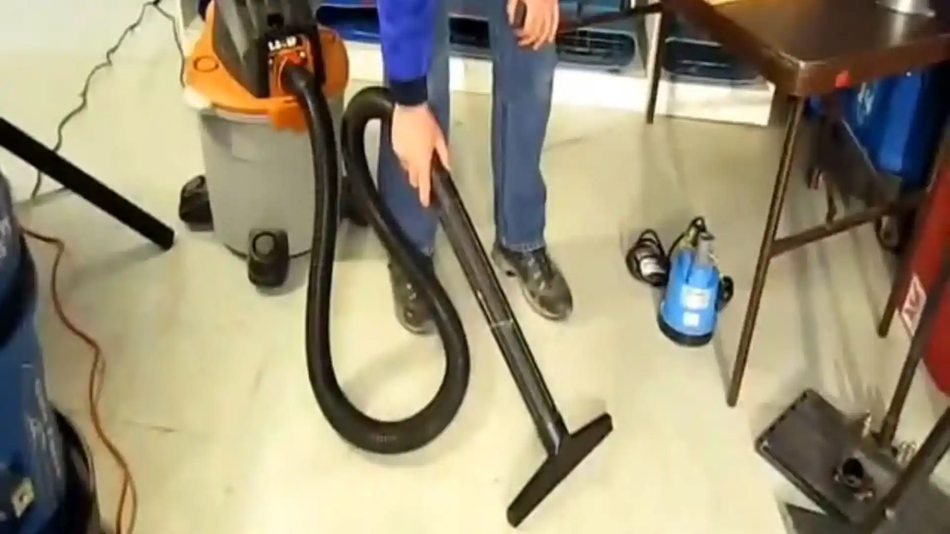 Wet-vac hose and a submersible pump on a hard floor during water extraction