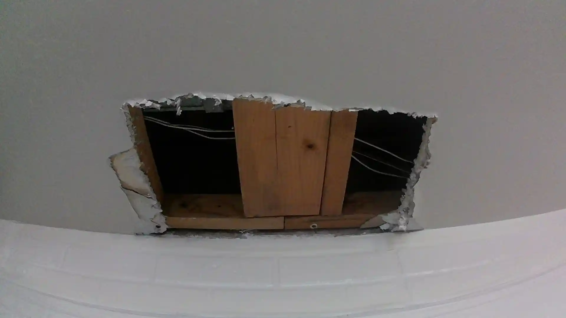 Cut-open ceiling section exposing framing and wiring after a water leak