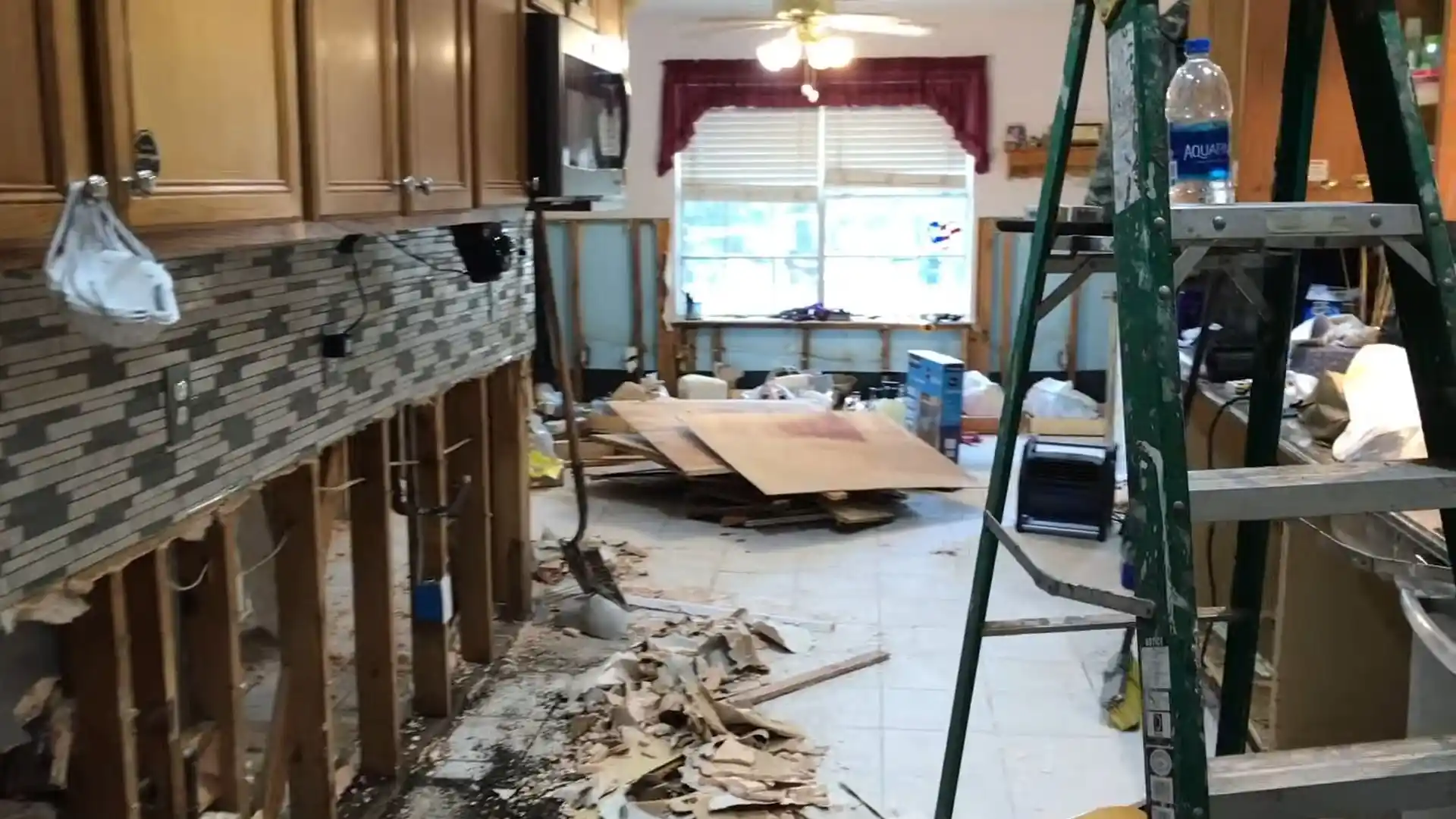 Kitchen with cabinets removed and debris piled on the floor during flood cleanup