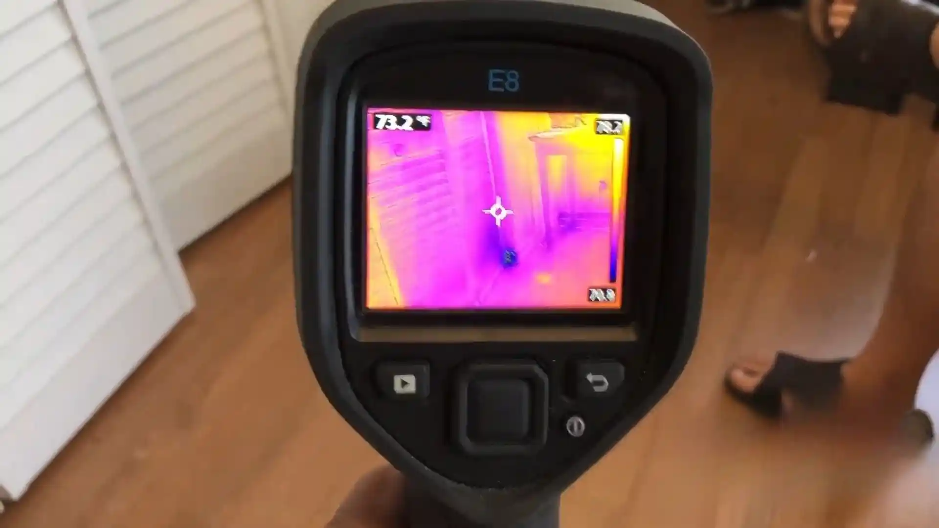 Thermal imaging camera displaying a heat-map view of a room during a moisture inspection