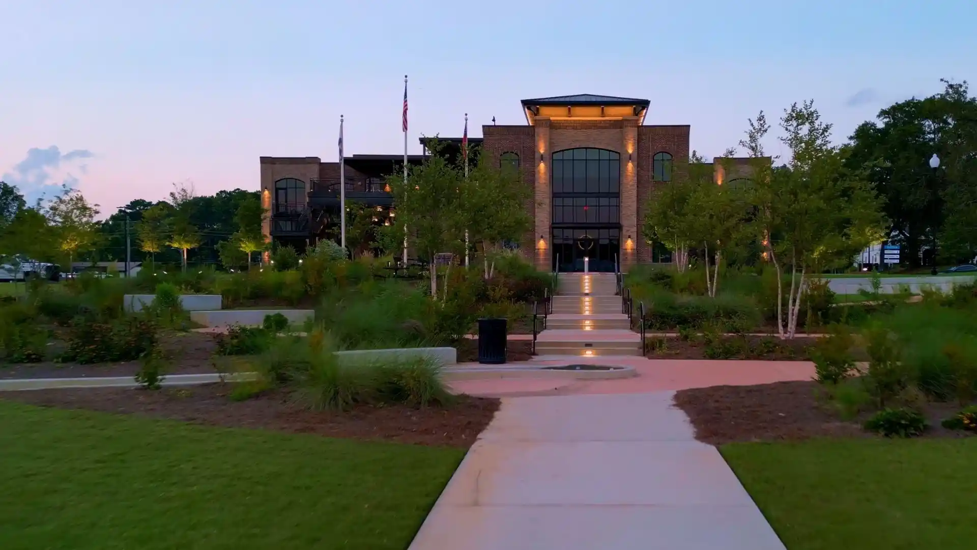 Brick civic building with an illuminated entrance and landscaped walkway in Fayette County, GA at dusk
