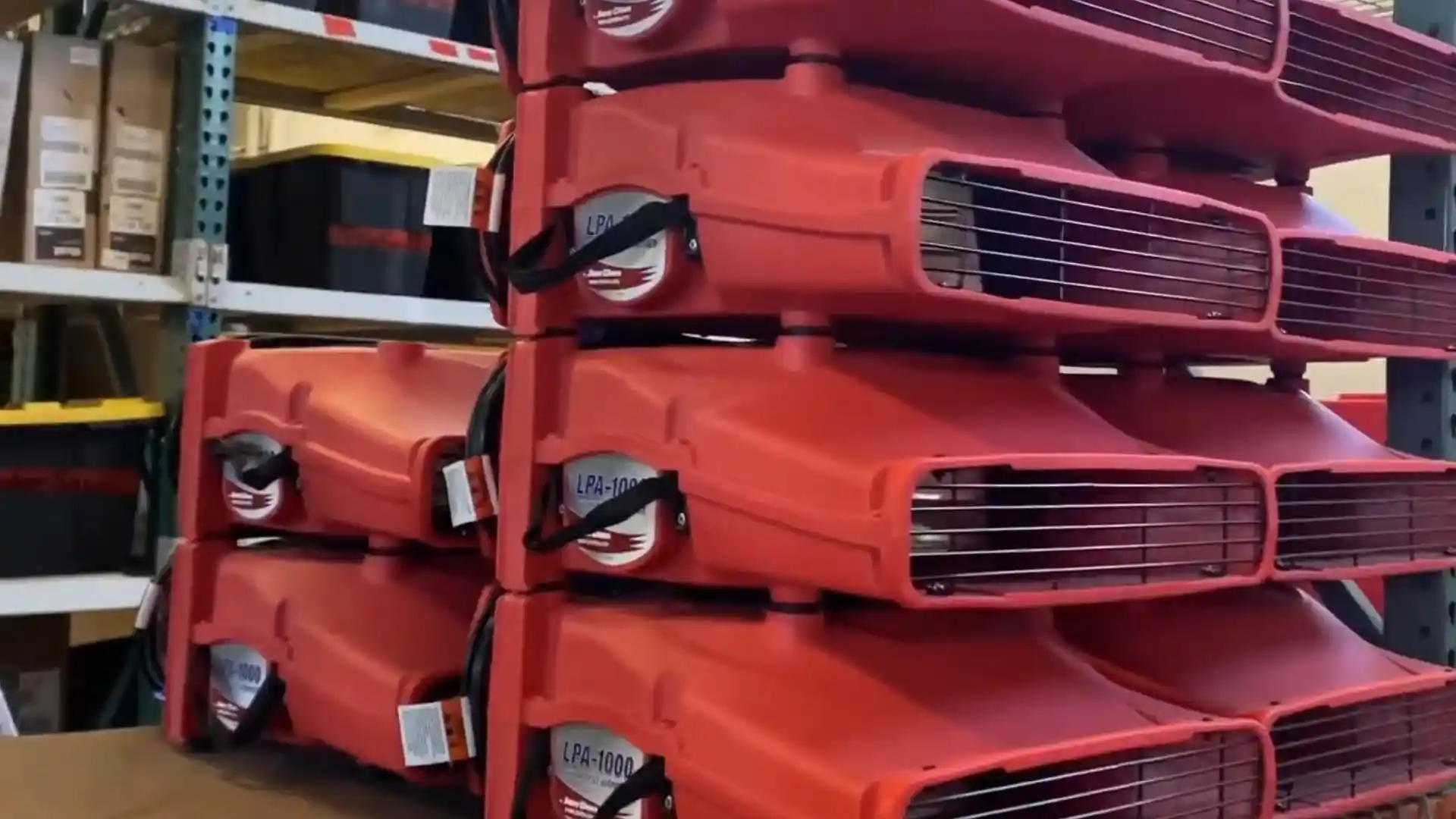 Stack of red air mover fans used for drying equipment in a restoration company's warehouse