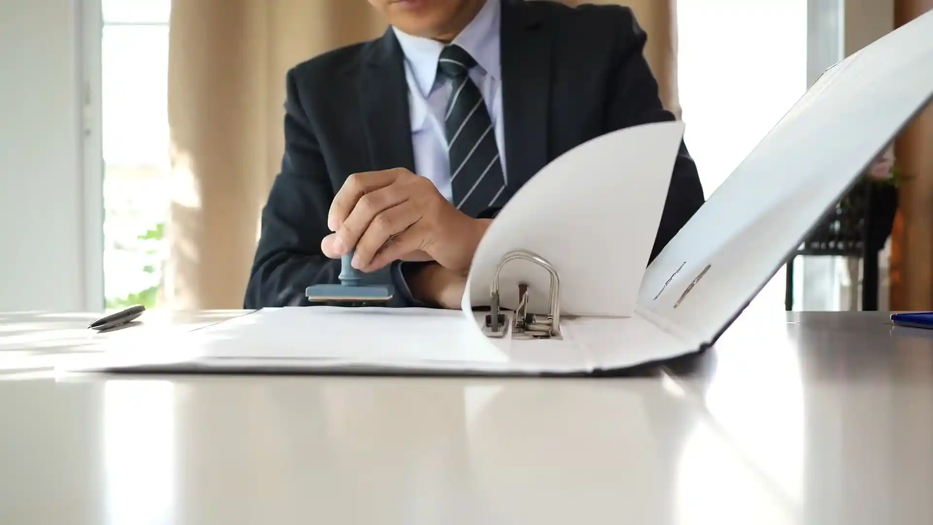 Person in a suit stamping a document in a binder